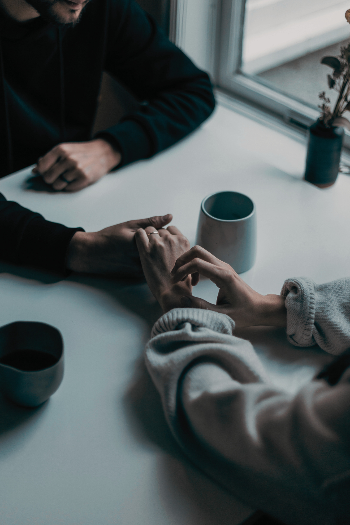 Two individuals holding hands while having coffee, symbolizing connection and support fostered by couples counselling services in maple ridge