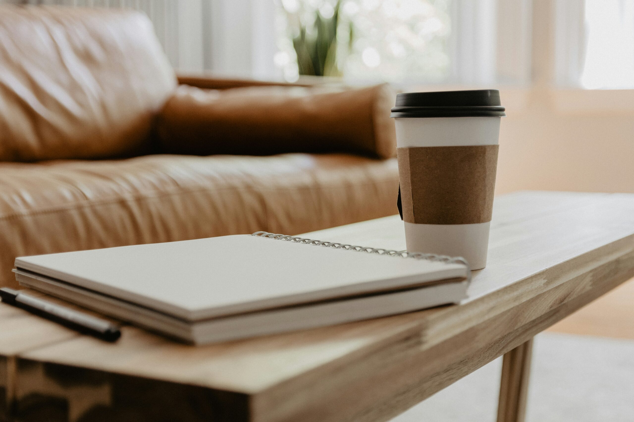 A notebook and coffee cup on a table evoke the constant doing, planning, and pushing that often leads to burnout. This image represents how stress and burnout counselling at Ignite helps clients slow down, understand their limits, and create healthier patterns that support long‑term steadiness.